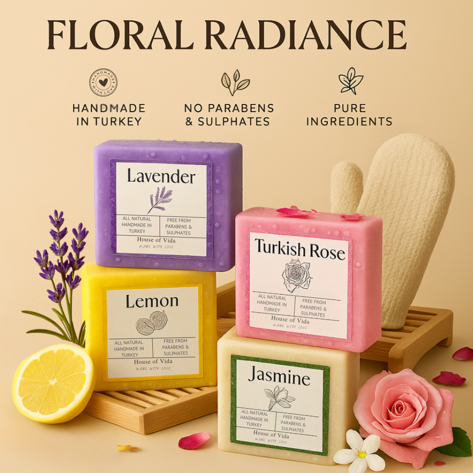 A set of four handmade soaps labeled Lavender, Turkish Rose, Lemon, and Jasmine, displayed with a lemon, soap dish, and exfoliating shower glove.