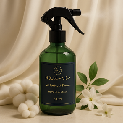 A green glass bottle of 'White Musk Dream - Luxe Home & Linen Spray' with a black spray nozzle. The bottle is labeled and contains 500ml of the fragrance.